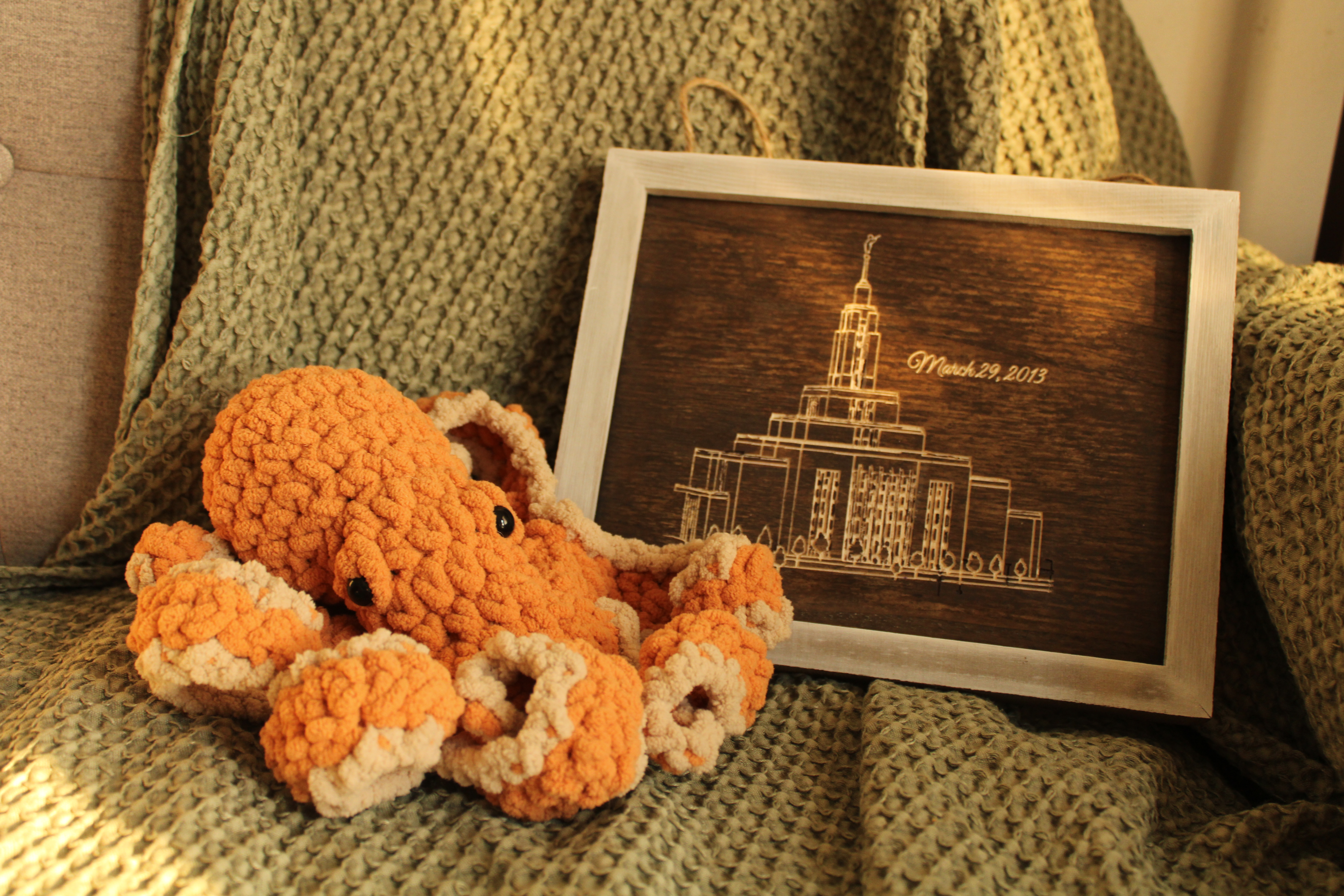 Handmade crochet octopus beside a framed wood engraving